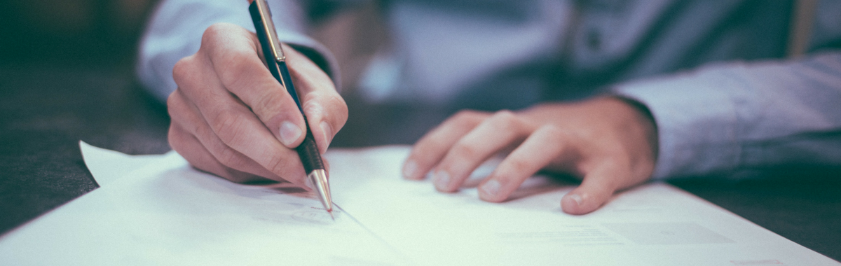 Dłonie mężczyzny piszącego na kartce.